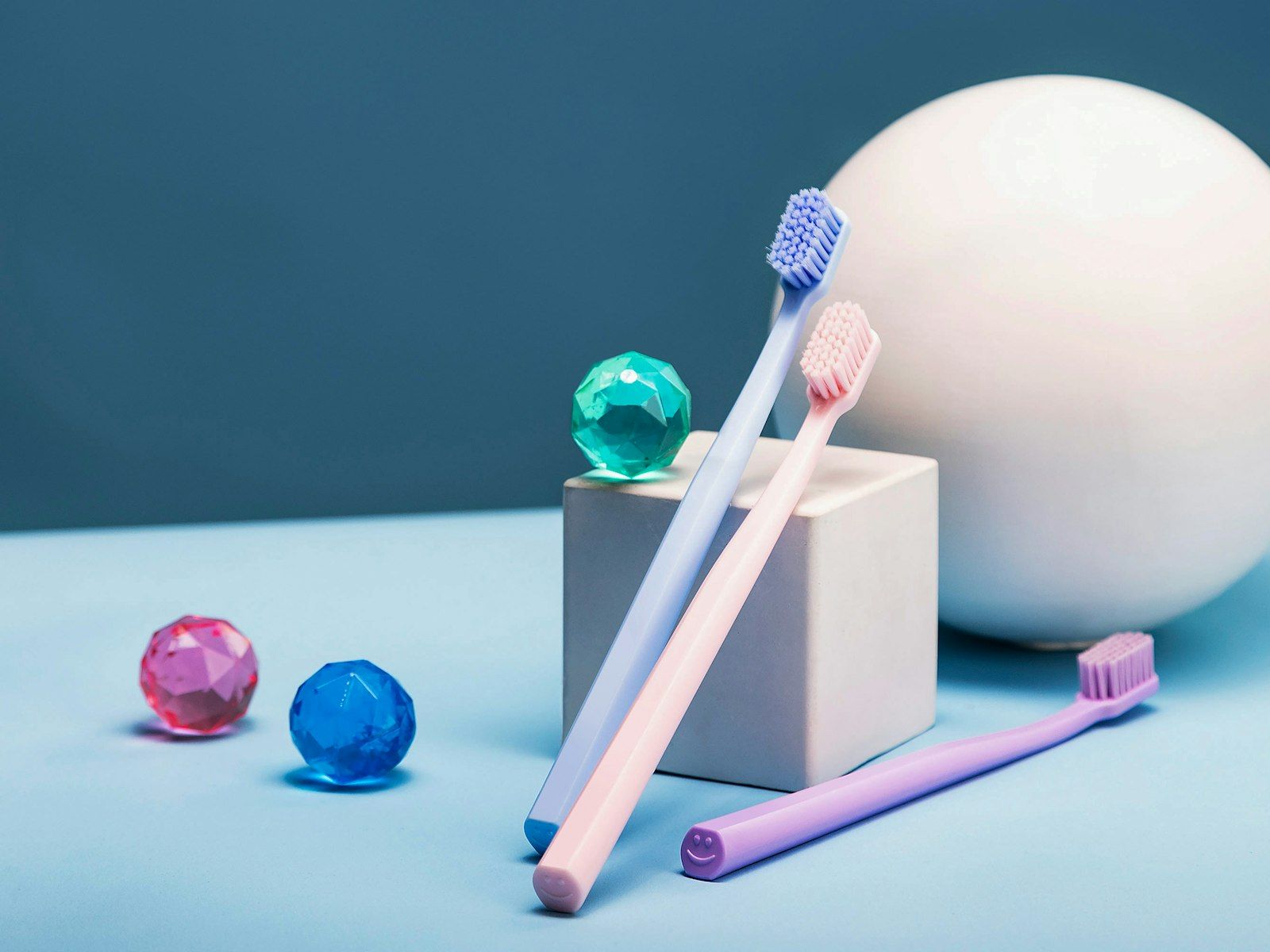 Cepillos de dientes de colores suaves junto a figuras geométricas de juguete.