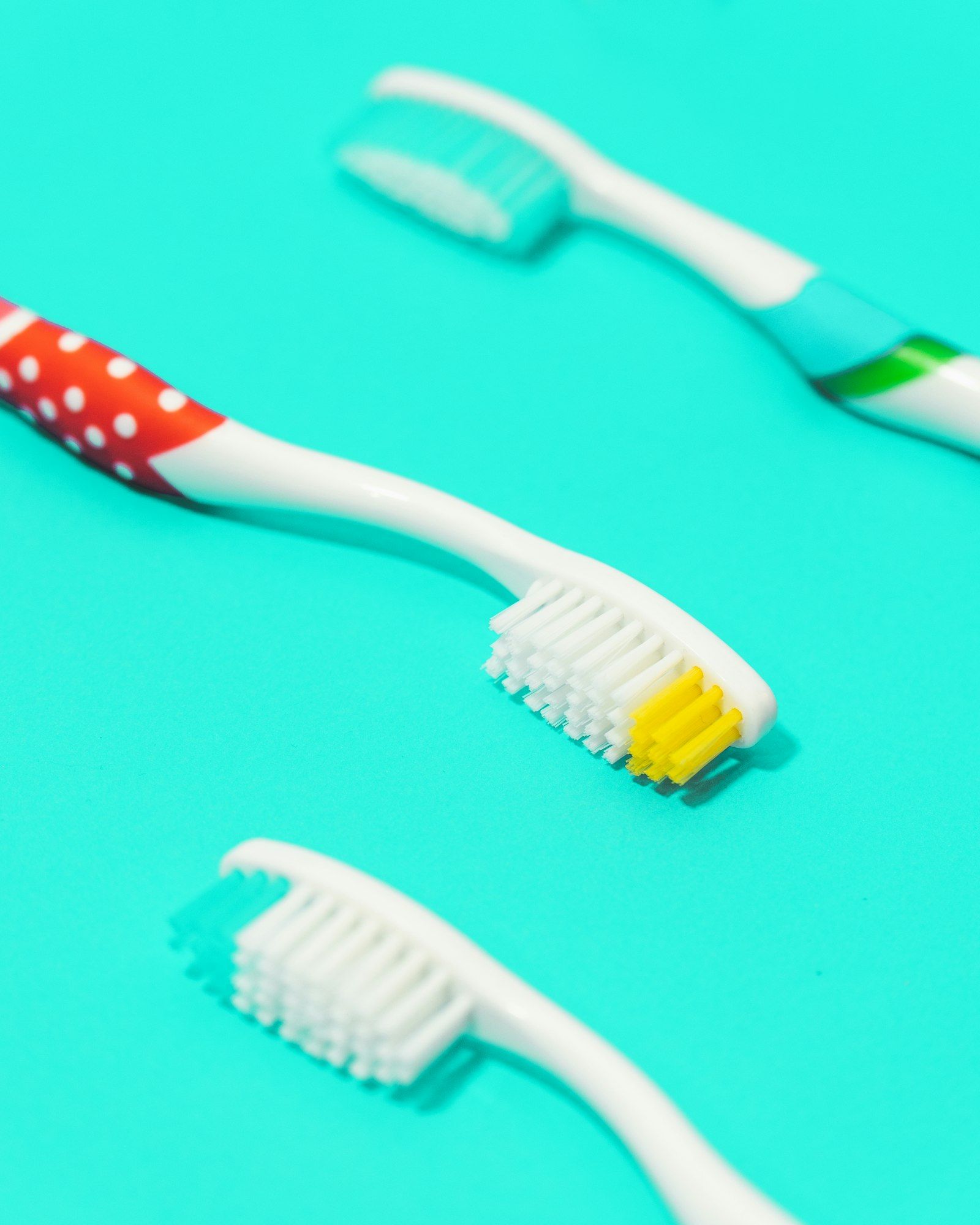 Cepillos de dientes infantiles de colores sobre fondo turquesa.